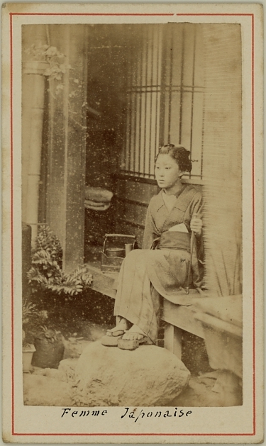 Japanese lady in kimono, seated in front of house.  Ca. 1875-80