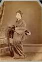 Geisha in traditional dress besides a Western style chair - Japanese photograph 1870's